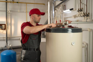 A man performing a service on a traditional tank water heater.