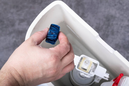 Homeowner dropping cleaning tablet in toilet tank.