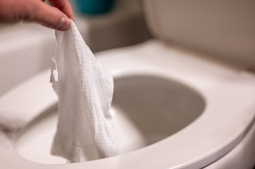 Homeowner throwing "flushable" wipe into the toilet.